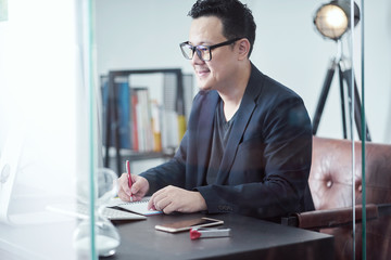 Young Asian businessman feeling happy while sitting at his working place .