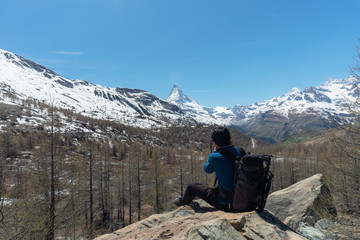 Wall Mural - travelling in switzerland, a man with backpack taking photograph of matterhorn mountain, alps mounta
