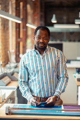 Canvas Print - Dark-skinned man standing near table in publishing office