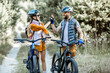 canvas print picture - Young and active couple giving a five each other, having fun while traveling with bicycles on the forest road