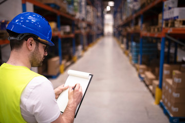 Wall Mural - Factory worker holding clipboard and checking inventory of warehouse storage department.