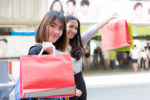 Happy Asian Girl Friends With Colourful Paper Bags  At Shopping Mall