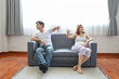 © feeling lucky - full shot of asian pregnant wife and caucasian husband sitting on sofa in living room with angry motion and showing thumb down or dislike something with unhappy face