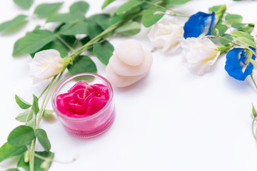 Red rose candle,beautiful butterfly pea flowers frame,green leaves and white stone on white background,top view