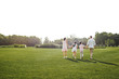 © Friends Stock - Power of family. Back view of young family of four holding hands and spending weekend together outdoors in park