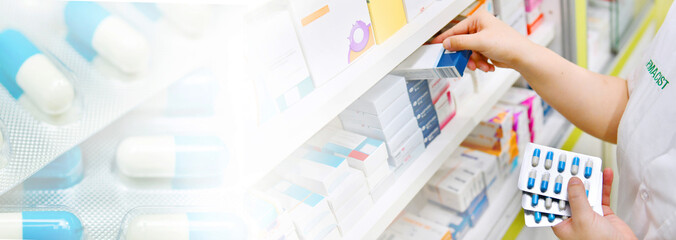 Pharmacist holding medicine box and capsule pack in pharmacy store and blue capsule pack background for copy space