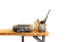 Tools For Pottery With Potters Wheel Are Standing On The Wooden Table In Messy Studio, White Isolated