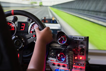 Racing Video Game Being Played By A Child On A Racing Simulator With Many Lights And Buttons.