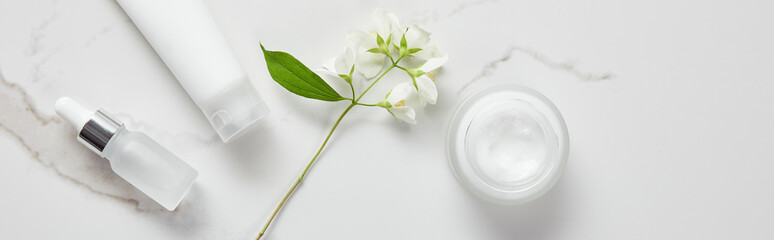 Poster - panoramic shot of jasmine, cosmetic glass bottle, jar with cream and moisturizer tube on white surface