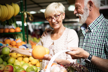 Wall Mural - Smiling senior couple buying vegetables and at the merket