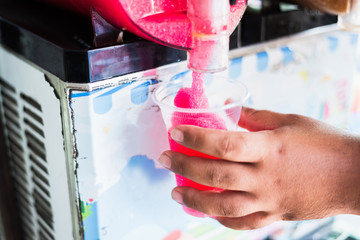 Human hand serving slushy drink from slushy  machine