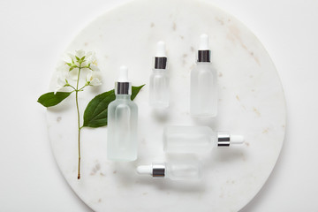 Wall Mural - top view of plate with jasmine and cosmetic glass bottles on white surface