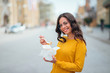 © bnenin - Girl eating take-away food in the city street, smiling at camera.