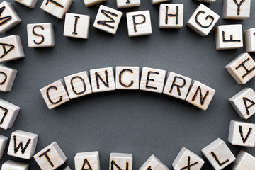 Fototapete - the word concern wooden cubes with burnt letters, gray background top view, scattered cubes around random letters