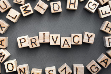 Fototapete - the word privacy wooden cubes with burnt letters, data confidentiality, gray background top view, scattered cubes around random letters