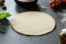 Raw Dough, Ingredients And Spices For Pizza Margherita With Tomato Sauce And Mozzarella Cheese On Black Background.