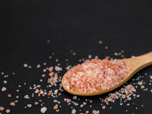 Healthy Spices Concept. Large Dark Pink Himalayan Salt In A Wooden Spoon And Spilled On A Black Table. Closeup