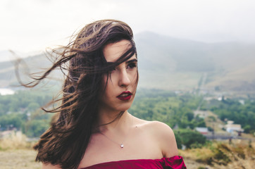 Wall Mural - Portrait of young woman in red dress standing near monastery, Armenia