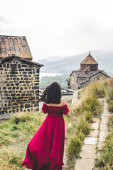 Wall Mural - Portrait of young woman in red dress walking near monastery , Armenia