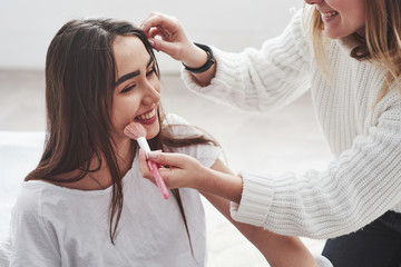 Two of them looks satisfied. Makeup artist use brush to put on powder. Conception of skincare