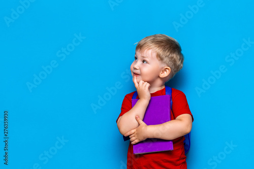 Fotomural Back to school Portrait of happy surprised kid in glasses isolated on blue background with copy space