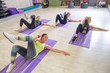 © AnnaDemy - Young fit Women on a Yoga Pilates group class in gym. They stretch, stay in asana poses in sport outfit. Daylight. Indoors
