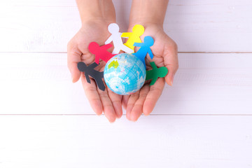 Woman holding globe with people chain made from paper cut. World population day.