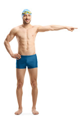 Wall Mural - Young man in swimming shorts, googles and a cap pointing to the side