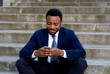 © SB Arts Media - Young business entrepreneur man sitting outdoors urban stairs working and using smart phone