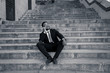 © SB Arts Media - Portrait of handsome african american businessman talking on mobile sitting outdoors on city stairs