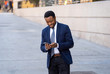 © SB Arts Media - Young handsome businessman using mobile phone app sending message outside office in urban city