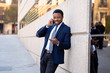 © SB Arts Media - Portrait of handsome african american businessman walking in the city talking on mobile phone