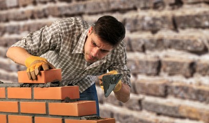 Wall Mural - Worker builds a brick wall in the house