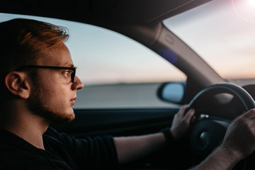 Wall Mural - driver of the car goes to meet the sun at dawn.