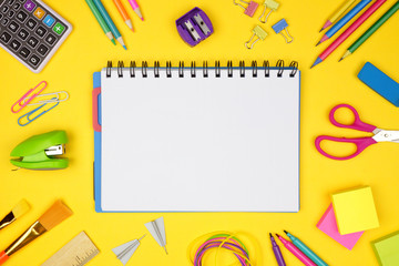 Wall Mural - Blank coil notebook with school supplies frame against a yellow background. Back to school concept. Copy space.