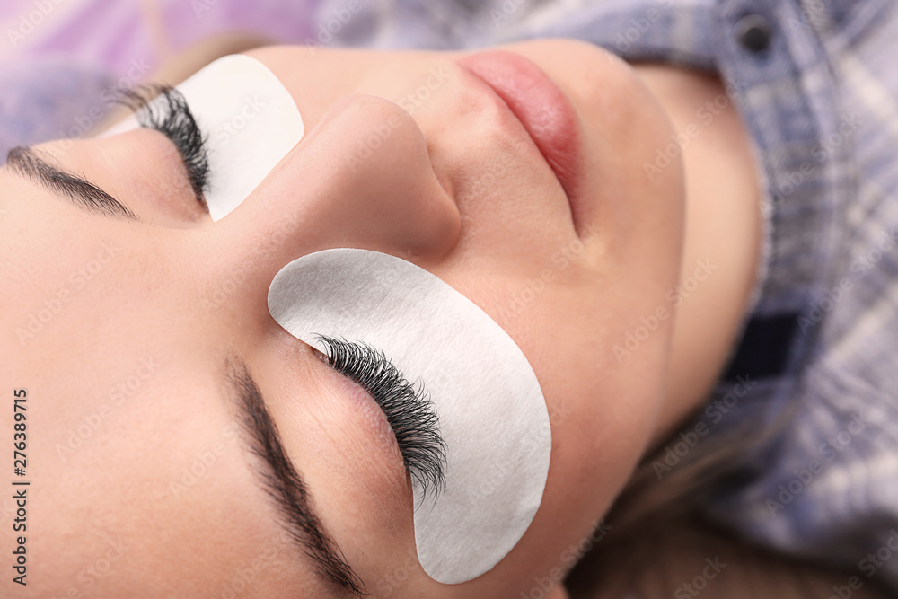 Young woman undergoing eyelash extensions procedure, closeup