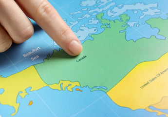 Woman pointing at Canada on map, closeup