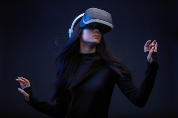 Wall Mural - beautiful woman with flowing hair in futuristic dress over dark background. girl in glasses of virtu
