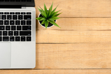 Wood office work space desk table with laptop and blank picture frame, small plant, pencil. Top view with copy space, flat lay.