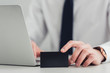 © LIGHTFIELD STUDIOS - partial view of businessman holding black empty business card while sitting at workplace in office