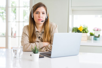 Canvas Print - Beautiful young operator woman working with laptop and wearing headseat skeptic and nervous, disapproving expression on face with crossed arms. Negative person.