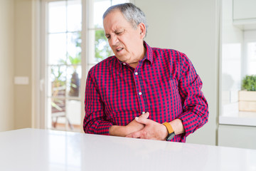 Sticker - Handsome senior man at home with hand on stomach because nausea, painful disease feeling unwell. Ache concept.