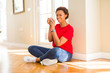 © Krakenimages.com - Beautiful young african american woman sitting on the floor at home and drinking a cup of coffee