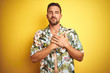 © Krakenimages.com - Handsome man wearing summer hawaiian flowers shirt over yellow isolated background smiling with hands on chest with closed eyes and grateful gesture on face. Health concept.