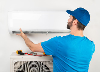 Installation service fix  repair maintenance of an air conditioner indoor unit, by cryogenist technican worker in blue shirt baseball cap