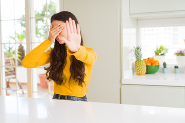 Sticker - Young beautiful woman at home on white table covering eyes with hands and doing stop gesture with sad and fear expression. Embarrassed and negative concept.