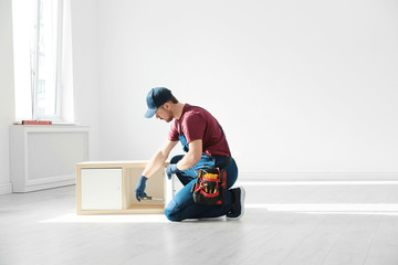 Wall Mural - Handyman in uniform assembling furniture indoors, space for text. Professional construction tools