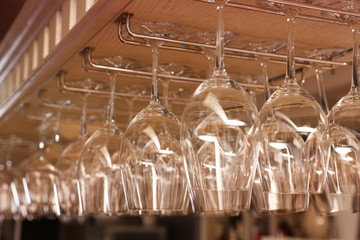 Set of empty clean glasses on bar racks