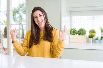 Sticker - Beautiful young woman wearing yellow sweater shouting with crazy expression doing rock symbol with hands up. Music star. Heavy concept.