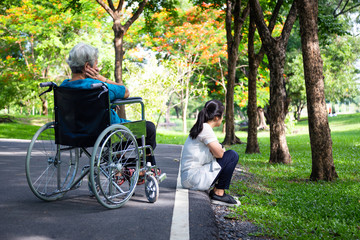 Asian adult woman touchy,angry acting with elderly people in wheelchair after senior mother argument,argue with daughter in outdoor park,relationship difficulties,conflict,hurt,family problems concept